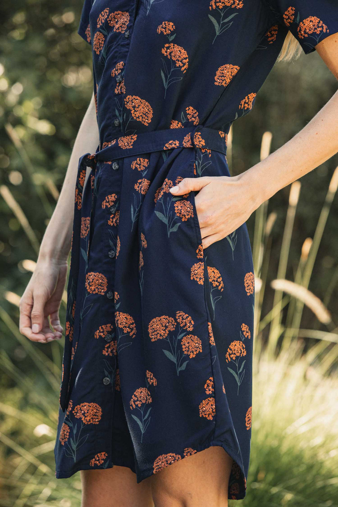 Bridge & Burn Sofia Shirt Dress in navy blue modal with an orange wildflower print, featuring a self-belted button front, a waist tie, and side pockets.