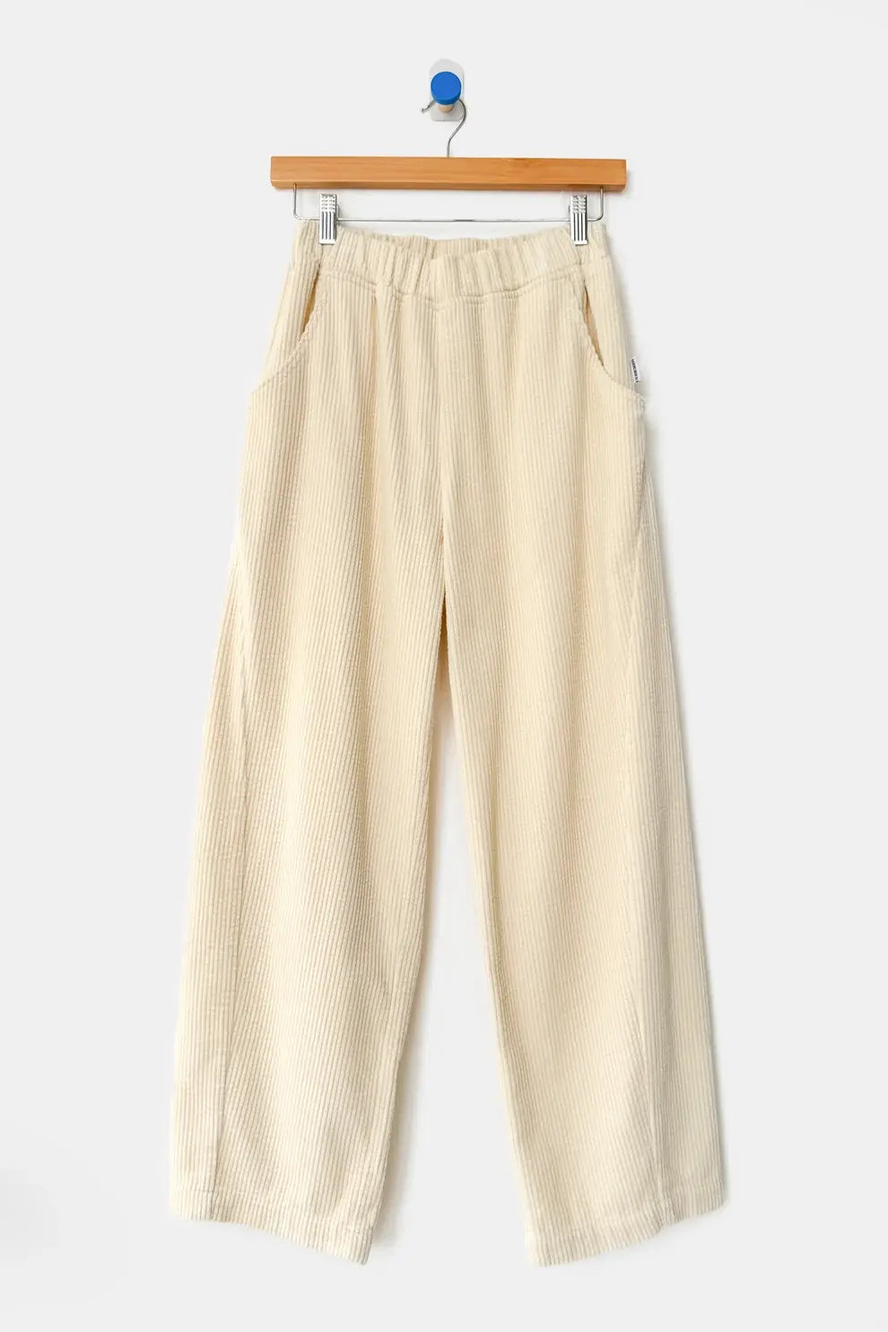 Le Bon Shoppe - Soft Corduroy Arc Pant / Ecru in off-white, featuring a high-waist, cropped wide-leg cut, elastic waistband, and side pockets, hanging on a wooden hanger.