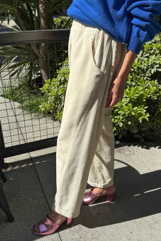 Person wearing Le Bon Shoppe - Soft Corduroy Arc Pant / Ecru trousers paired with metallic pink heeled mules.