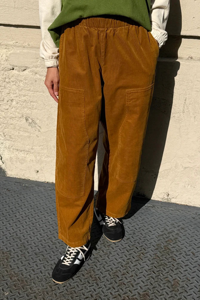 Person wearing Le Bon Shoppe Gardener’s Pant in Whiskey Corduroy with large patch pockets and an elastic waistband, paired with black sneakers.