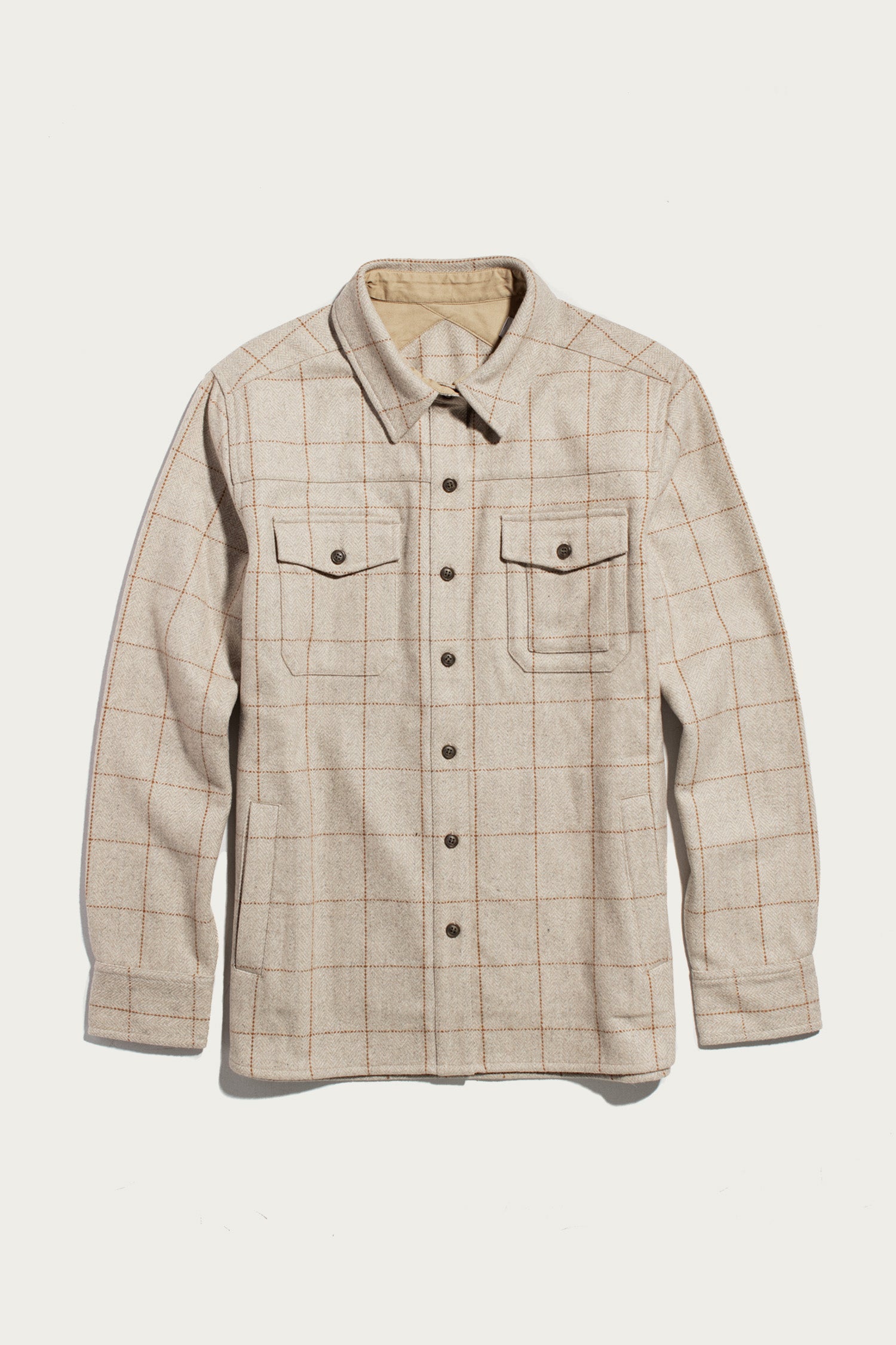 The Bridge & Burn Harlow Shirt Jacket in Stonecross features a beige plaid pattern, heavy-weight fabric, pointed collar, two flap chest pockets, and long sleeves, shown laid flat on a white background.