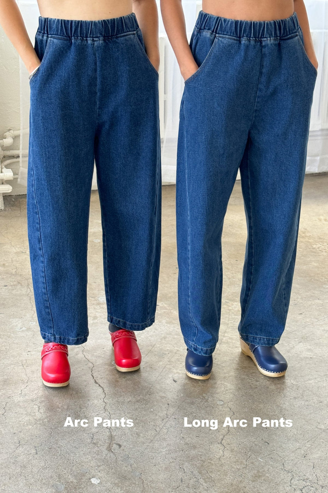 Two people stand side by side wearing blue denim pants and clogs. The person on the left wears Arc Pants crafted from heavyweight denim, ending above the ankle, while the person on the right wears Le Bon Shoppe - Long Arc Pant / Blue Denim by Le Bon Shoppe, featuring an extended inseam that reaches down to their shoes.