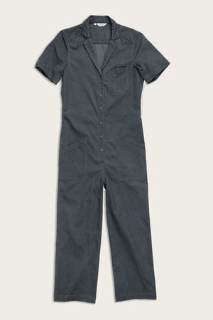 The Lou Utility Jumpsuit in Slate by Bridge & Burn is a dark gray, short-sleeve jumpsuit with a collar, adjustable front buttons, chest pocket, and two large front pockets, crafted from textural fabric and shown laid flat on a light background.