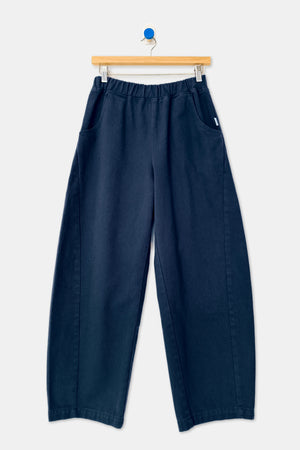 Le Bon Shoppe - Arc Pant in navy blue, featuring a high-waisted, wide-leg silhouette with an elastic waistband and side pockets, hanging on a wooden hanger.