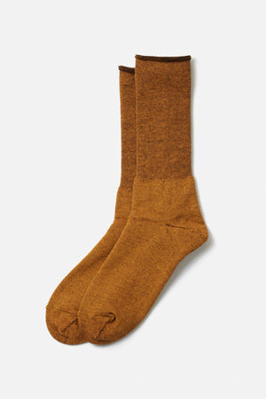 A pair of RoToTo City Socks in yellow brown, crafted from soft merino wool with a textured finish, shown overlapping on a plain white background.