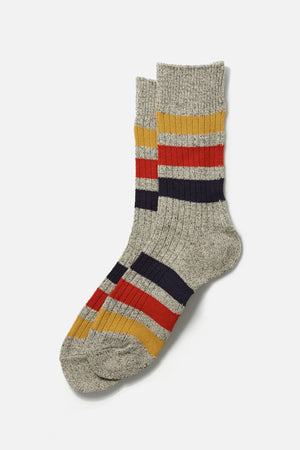 A pair of RoToTo Park Stripe Crew Socks in medium grey with mustard yellow, red, and navy blue horizontal stripes on the cuffs, ankles, and feet is shown on a white background.