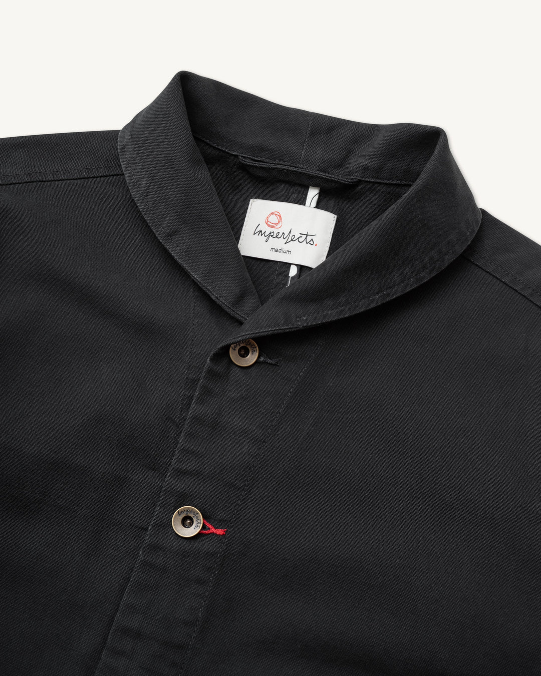 Close-up of an Imperfects Shepherds Shirt Craft Canvas in Obsidian, a black long-sleeved shirt featuring a shawl collar and dark buttons.