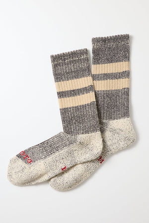 RoToTo Pile Stripe Marl Socks in Black Beige by RoToTo, made in Japan, feature a speckled gray foot, ribbed black and beige striped cuffs, and red text near the toes, shown on a white background.