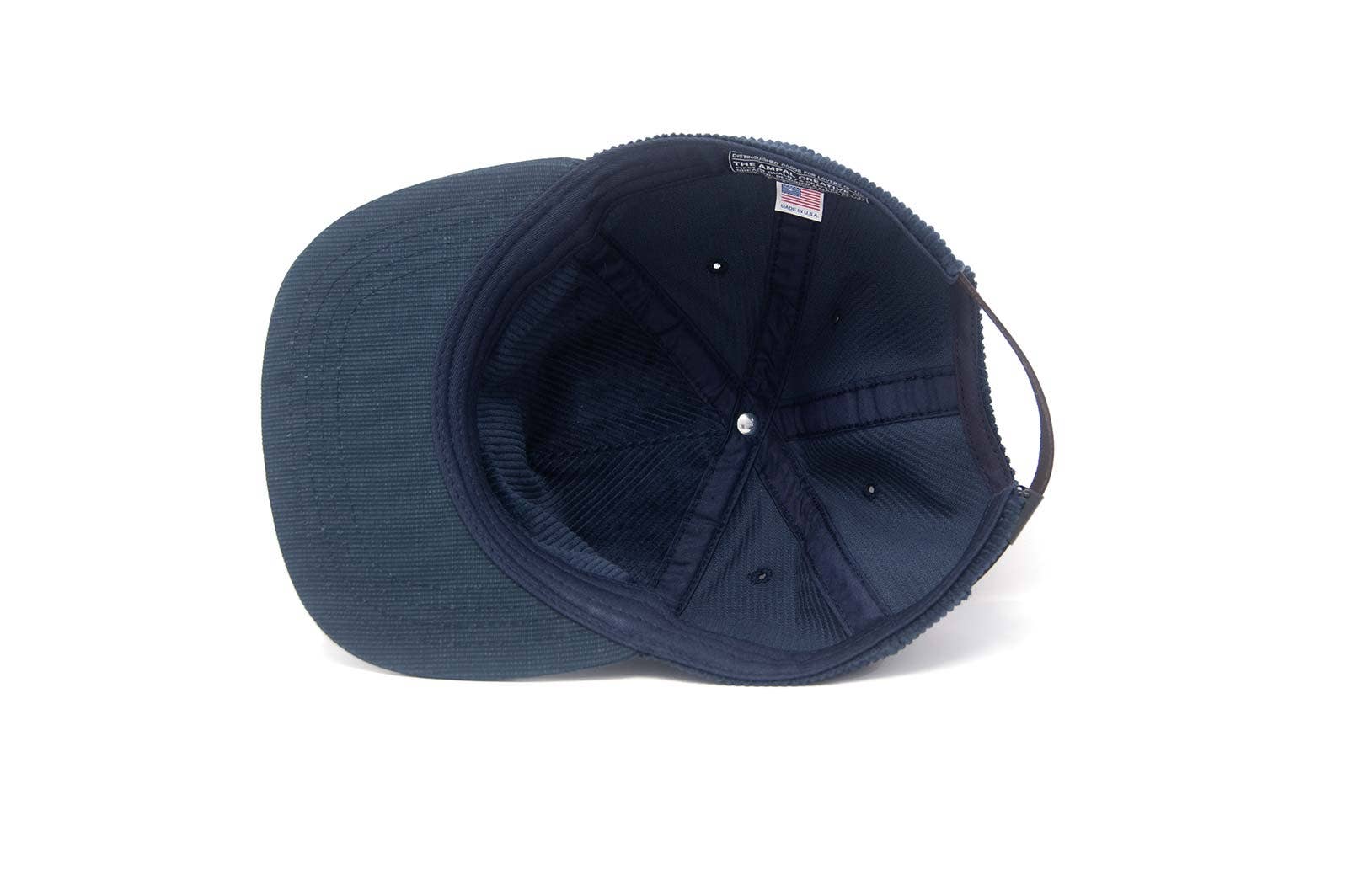 The Ampal Creative - Pacific III Strapback / Navy is shown inside-out, highlighting its stitching, fabric sweatband, and small American flag tag near the adjustable strap—classic vintage-style details—all set against a white background.