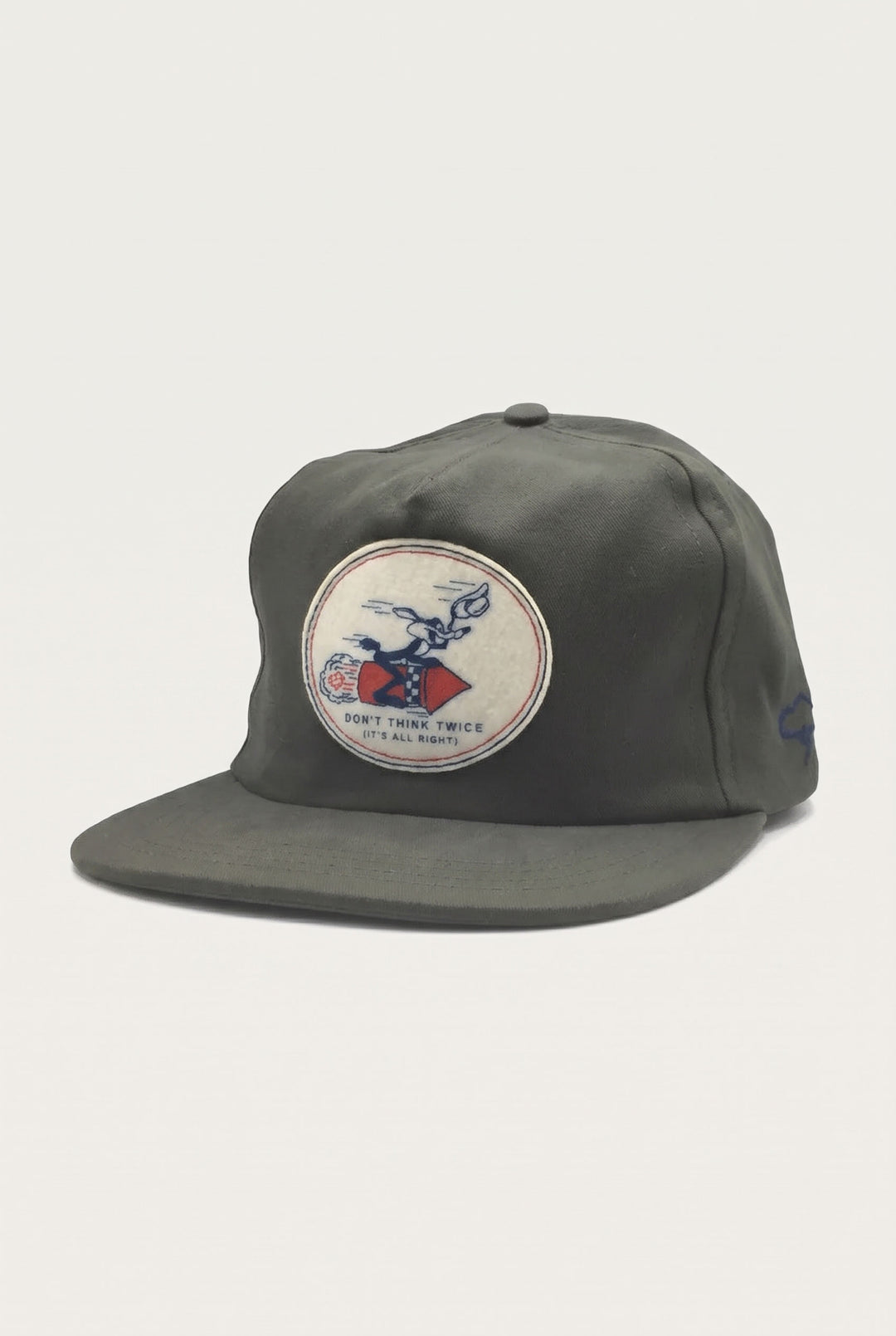 The Ampal Creative - Don’t Think Twice Strapback / Olive is an olive green cotton twill strapback cap featuring a round patch of a cartoon rabbit riding a rocket with the text Don’t think twice (it’s all right).