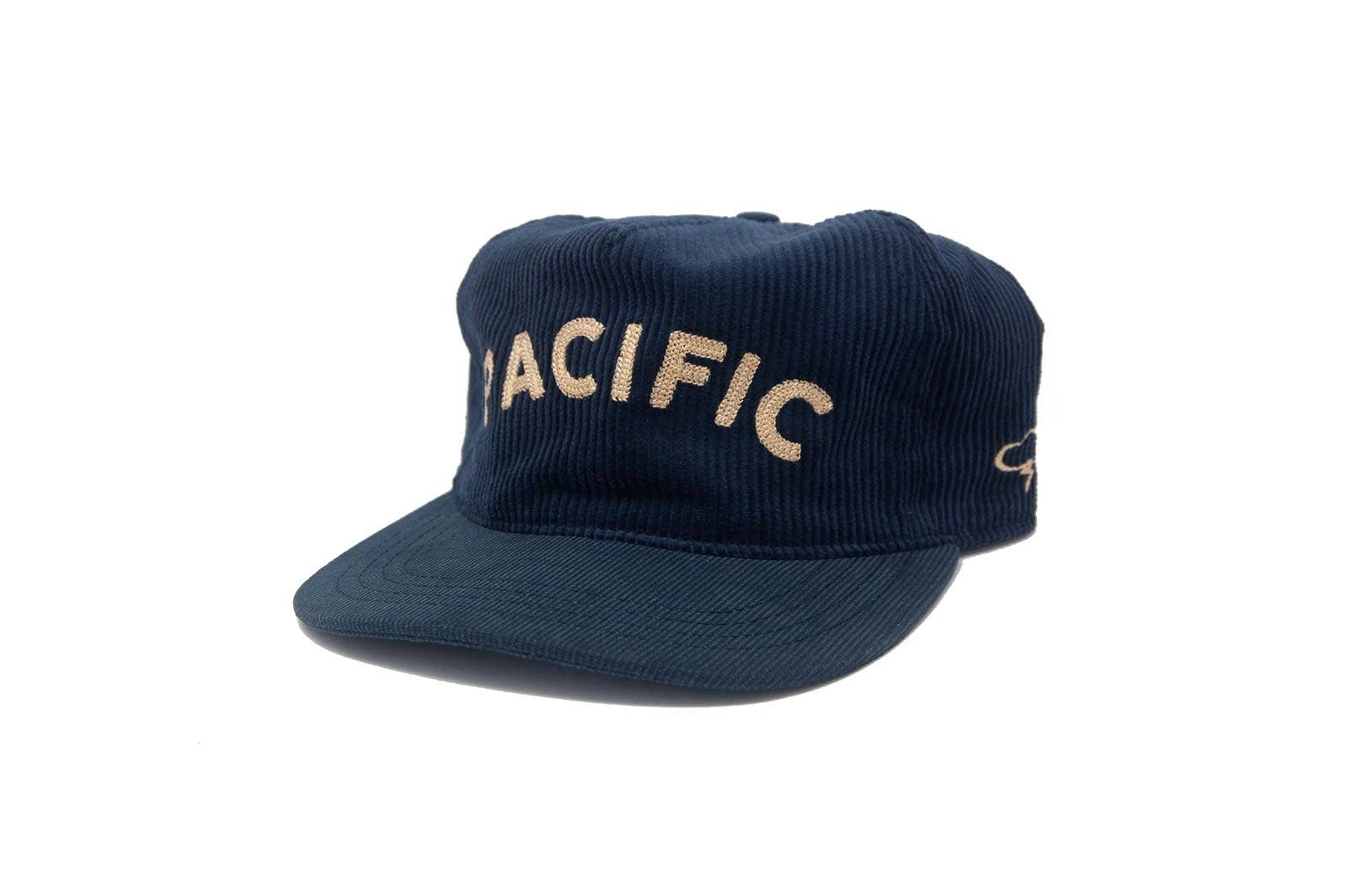 The Ampal Creative - Pacific III Strapback in navy features large beige vintage-style “PACIFIC” embroidery on the front, shown against a white background.
