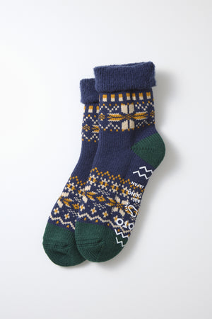 A pair of RoToTo Comfy Room Snow Flake Socks in navy, featuring green toes and heels, a yellow and white geometric pattern, and folded cuffs, made in Japan by RoToTo, displayed on a white background.