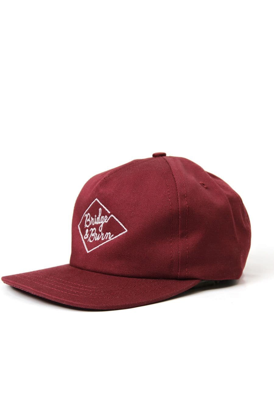 The Bridge & Burn Diamond Head Cap in Burgundy is a maroon baseball cap with a flat brim, featuring the white Bridge & Burn logo embroidered inside a diamond outline on the front. Made from durable cotton twill, this pinch front hat includes a leather adjustment strap for a comfortable, customizable fit. The cap is photographed against a plain white background.