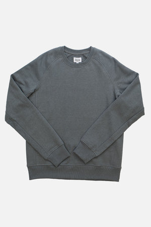 The Bridge & Burn Fremont Crew Sweatshirt in Storm Blue features long sleeves, ribbed cuffs, and hem. Shown laid flat on a white background, this sustainable piece offers a classic crewneck design.